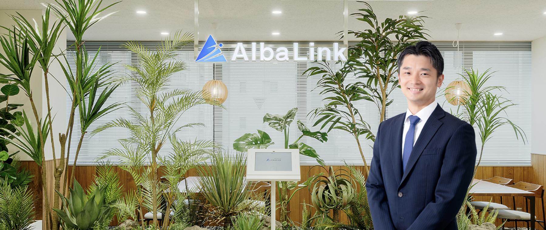 株式会社AlbaLinkの代表取締役がオフィス内で撮影された写真で、経営方針やビジョンを語る代表挨拶に用いられている図